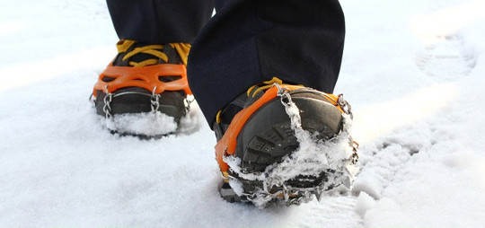 Boots with ice grippers walking in snow