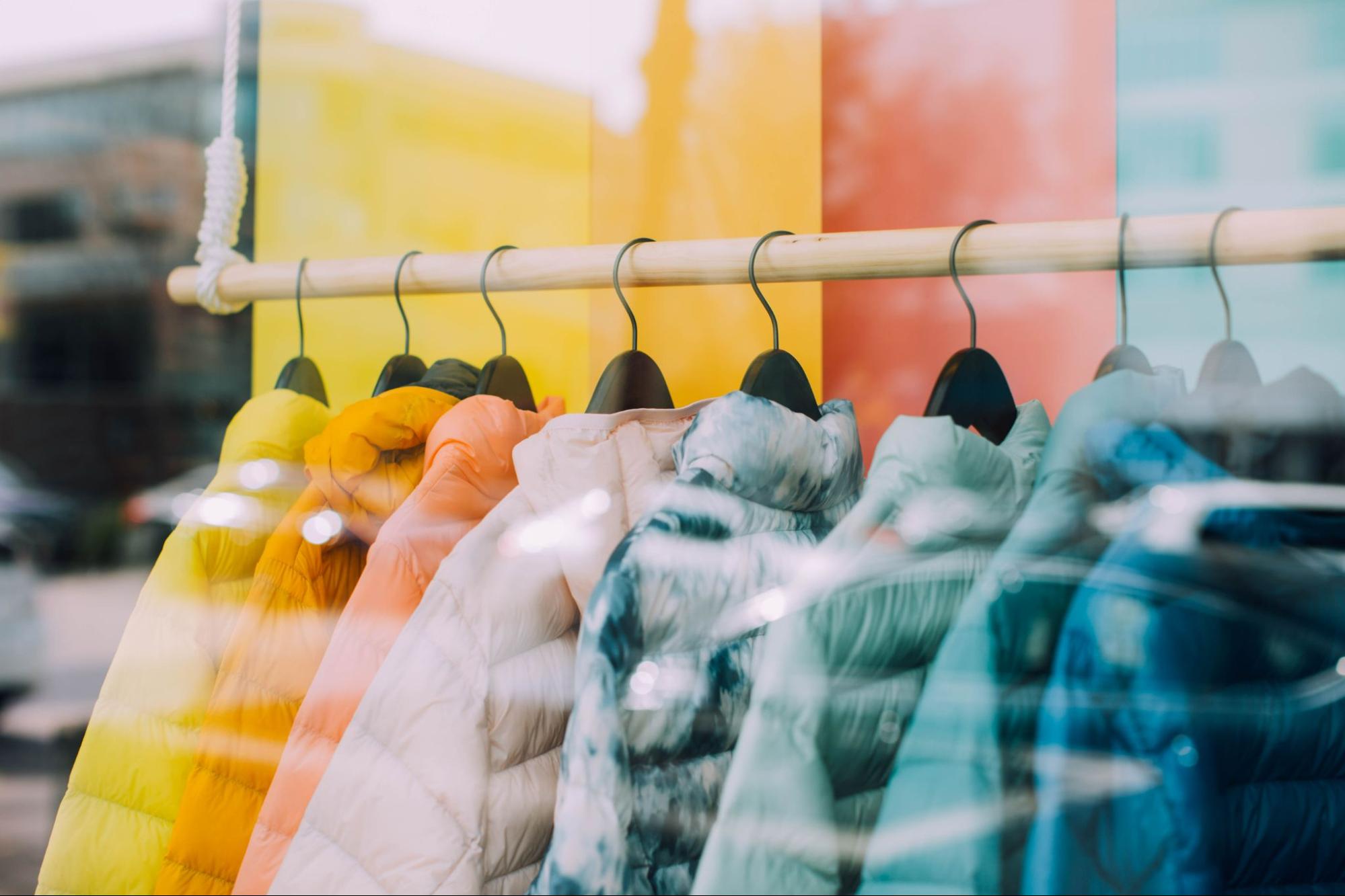 colorful winter coats hung in a store window